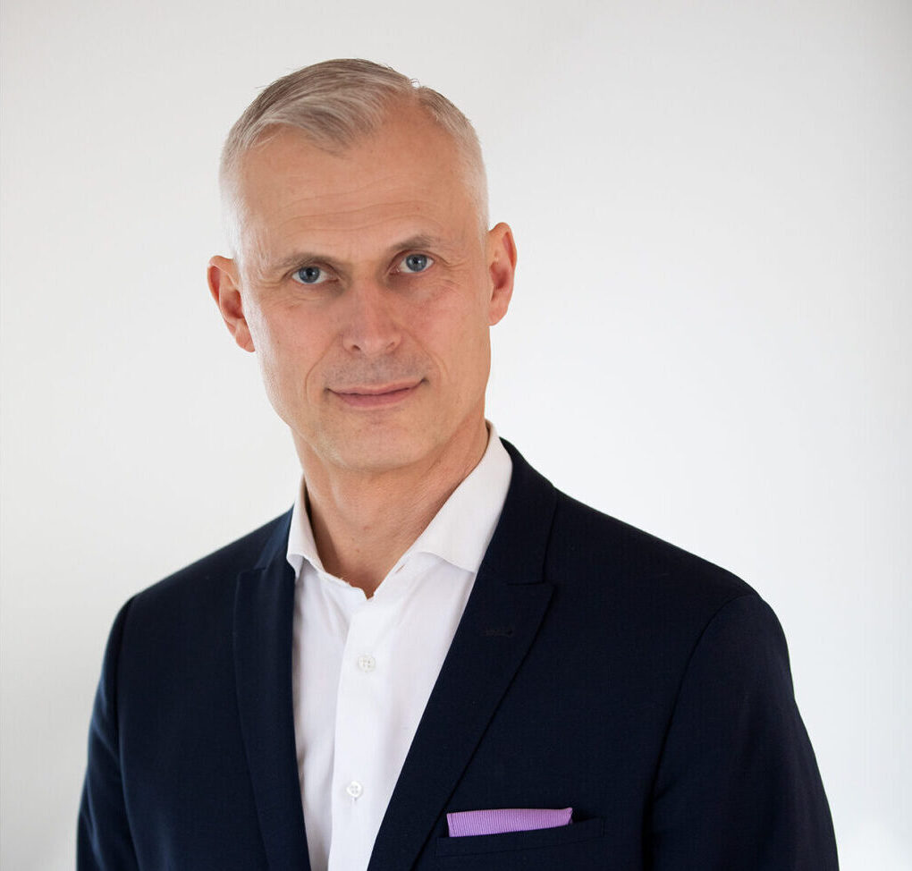 Martin waering a dark suit and whit shirt and is looking friendly into the camera, portrait photo