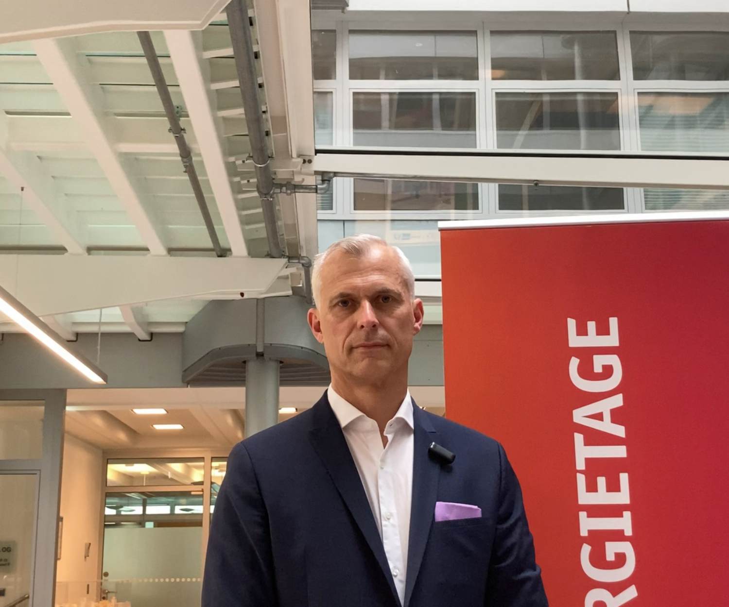 Portraitbild von Martin im Busineslook als Redner vor einem Roll up der Berliner Energietage